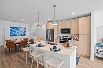 an open kitchen and dining area with a white counter top at Altis Grand Suncoast, Land O' Lakes, FL